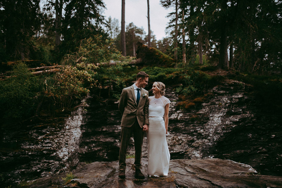 bride and groom holding hands with nature reserve of mar lodge behind them