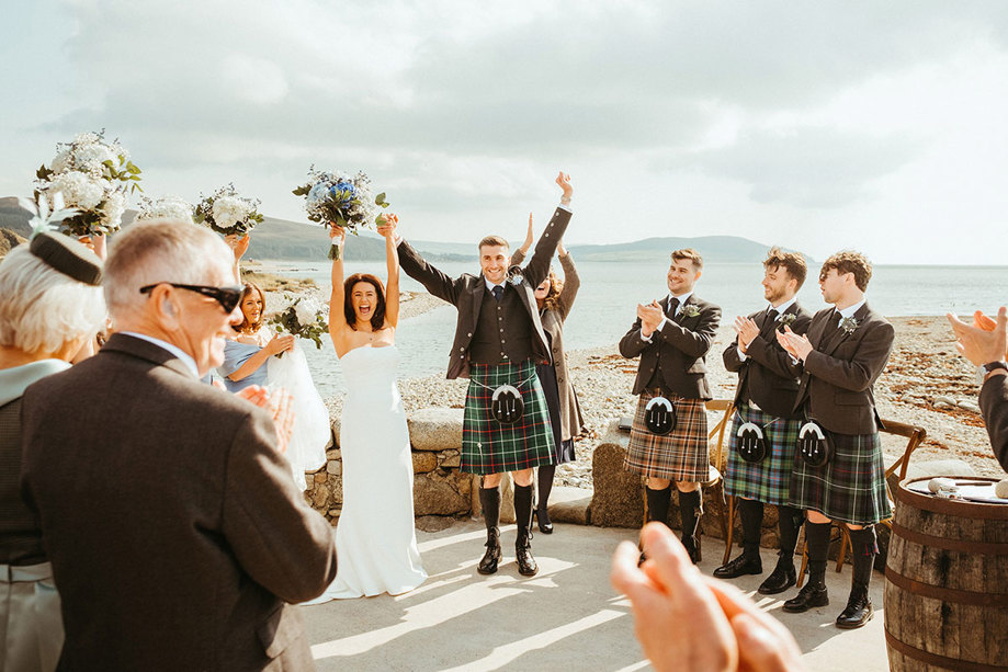 bride and groom cheer bride with guests during outdoor wedding ceremony at dougarie boathouse