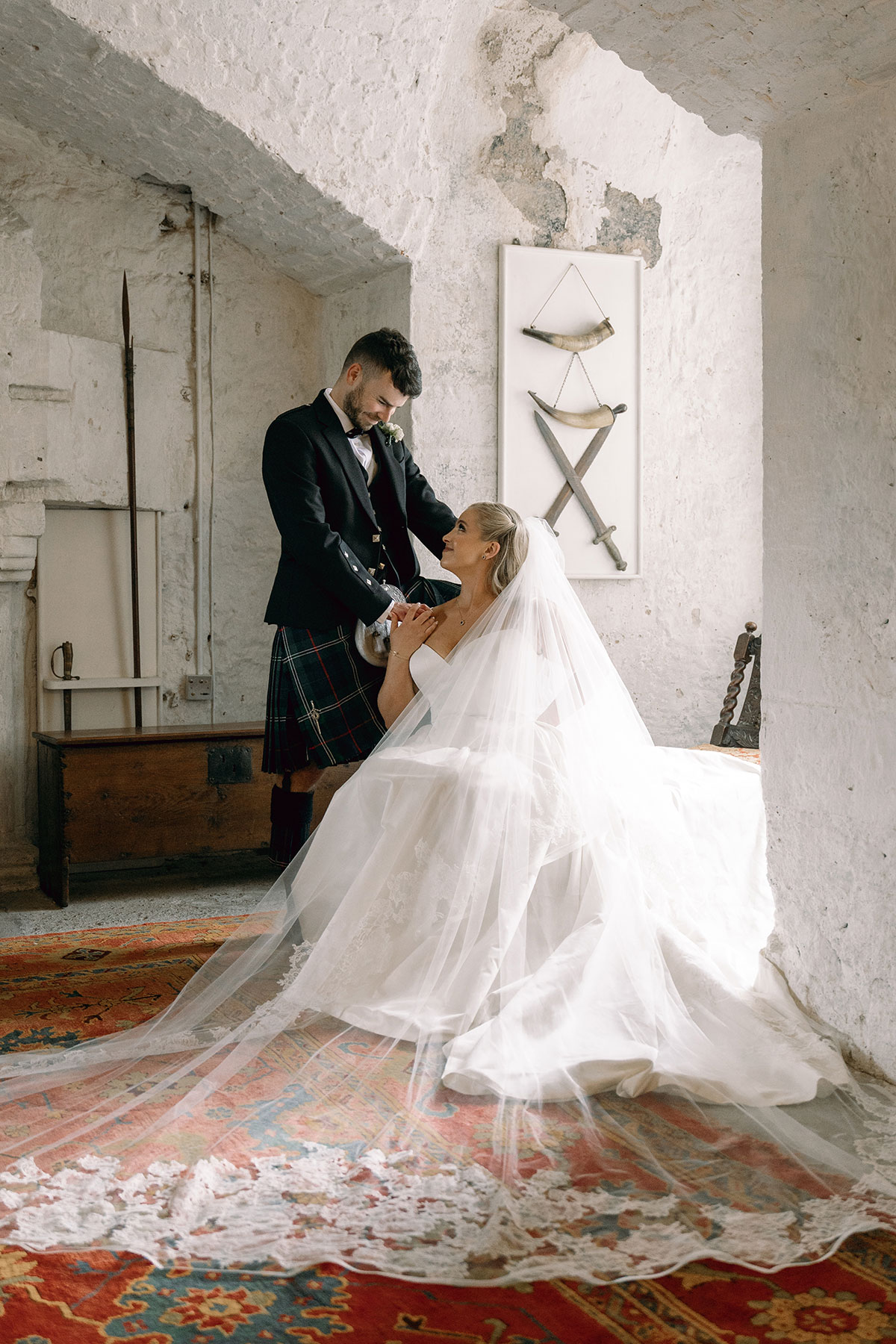Bride and groom share a quiet moment inside Dundas Castle’s stone chamber with lace veil and kilted attire.