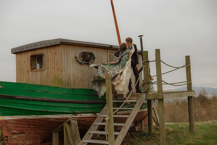 bride and groom kiss outside shipwrecked boat at guardswell farm