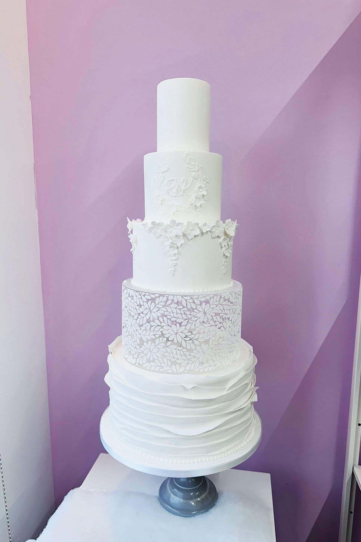 a five tier wedding cake with white icing and white icing flowers white one clear case tier