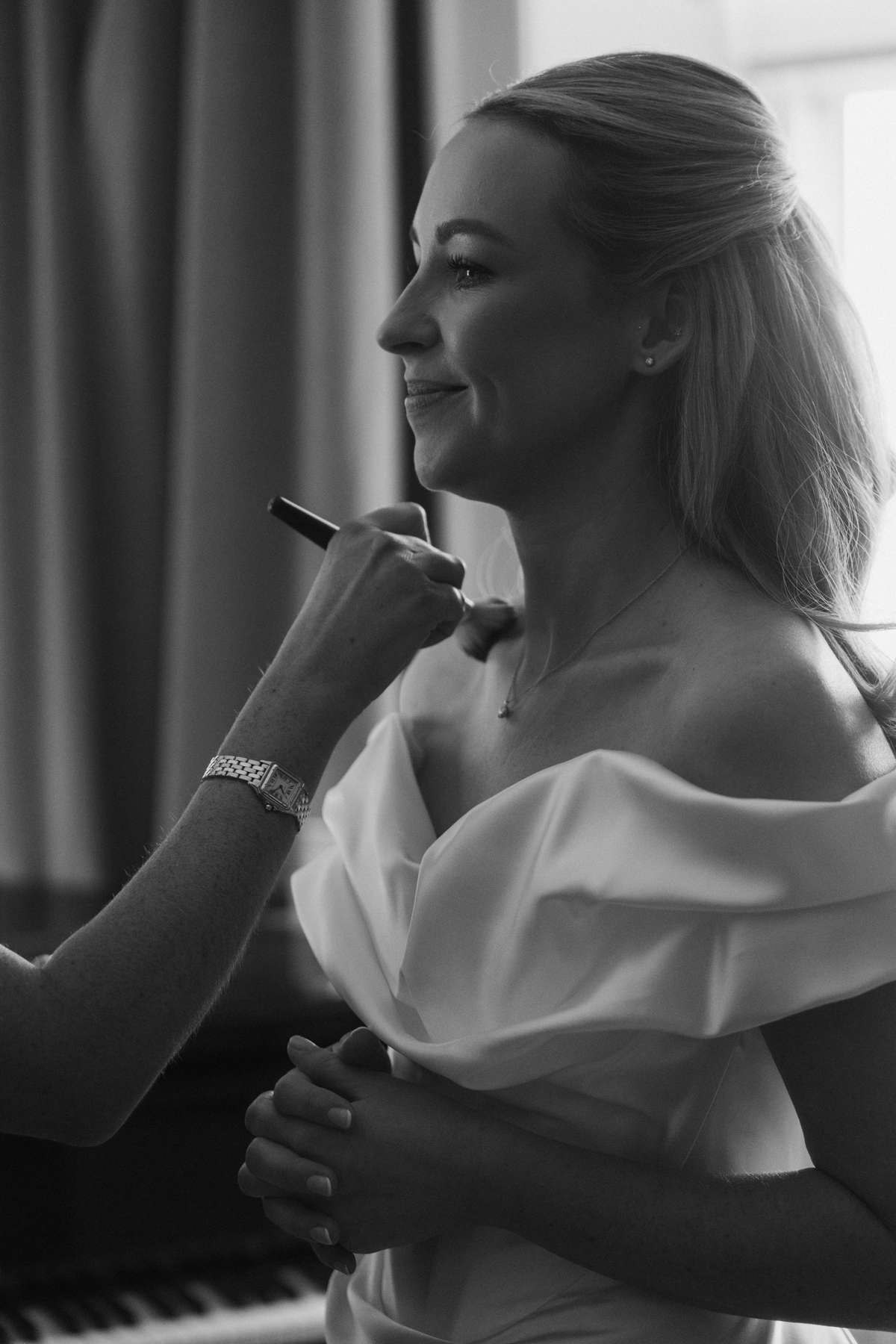 Black-and-white photo of bride Siân having the finishing touches applied to her makeup before her Mar Hall wedding ceremony.