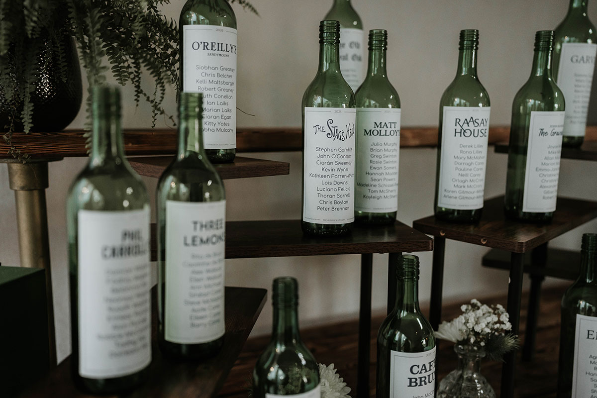 Wedding table plan made from green wine bottles with custom pub-themed labels 