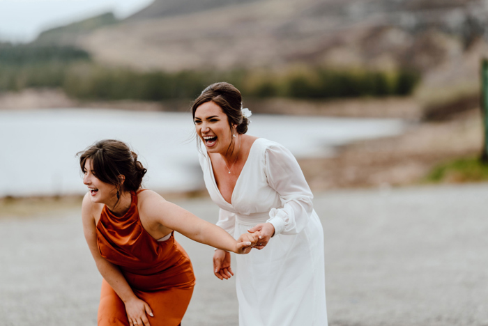 Bride and bridesmaid laugh on beach