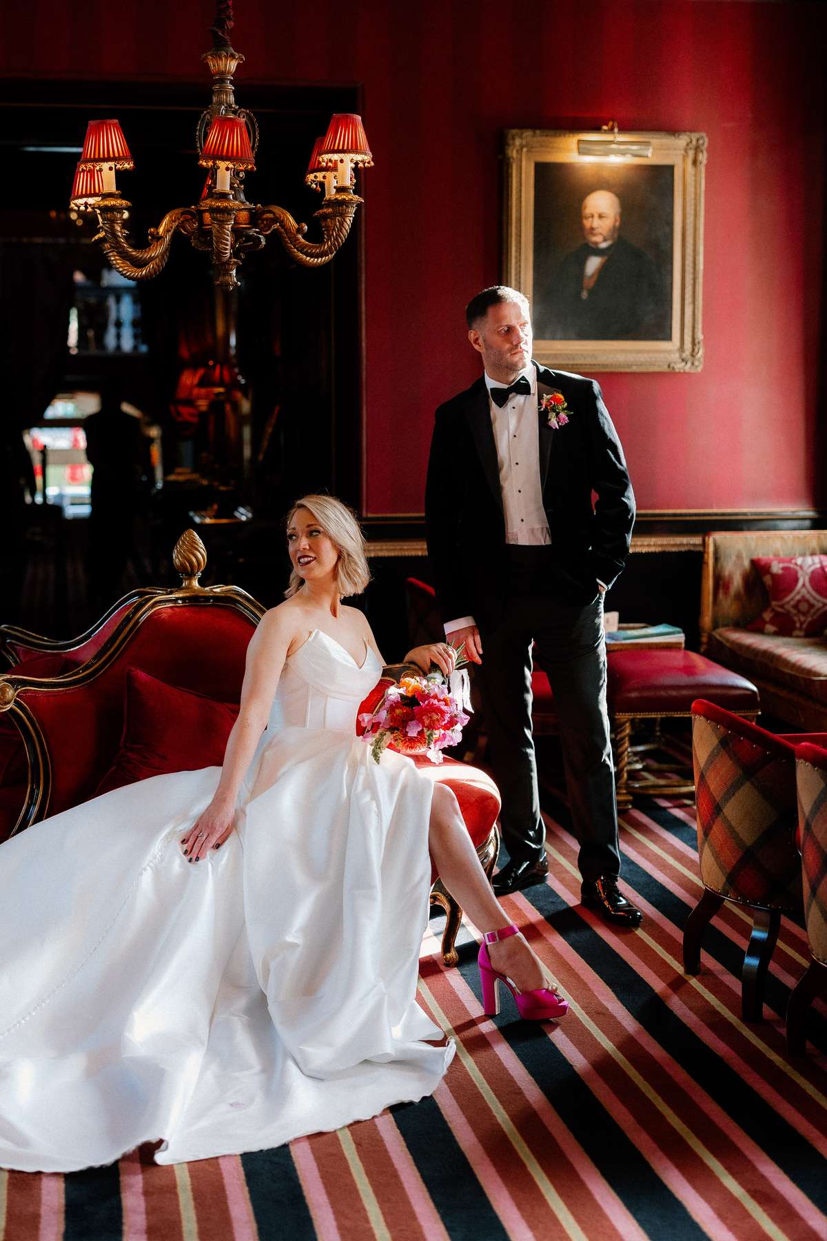 Kara and Rory pose for wedding portraits in the red interiors of Prestonfield House in Edinburgh.