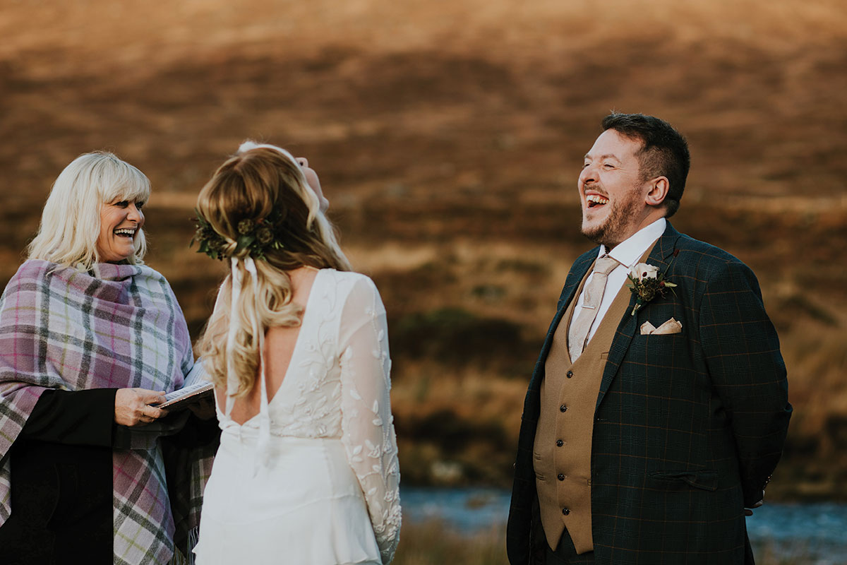 Niki Smith Fulcrum Foundation celebrant laughs while conducting wedding ceremony outside with bride and groom