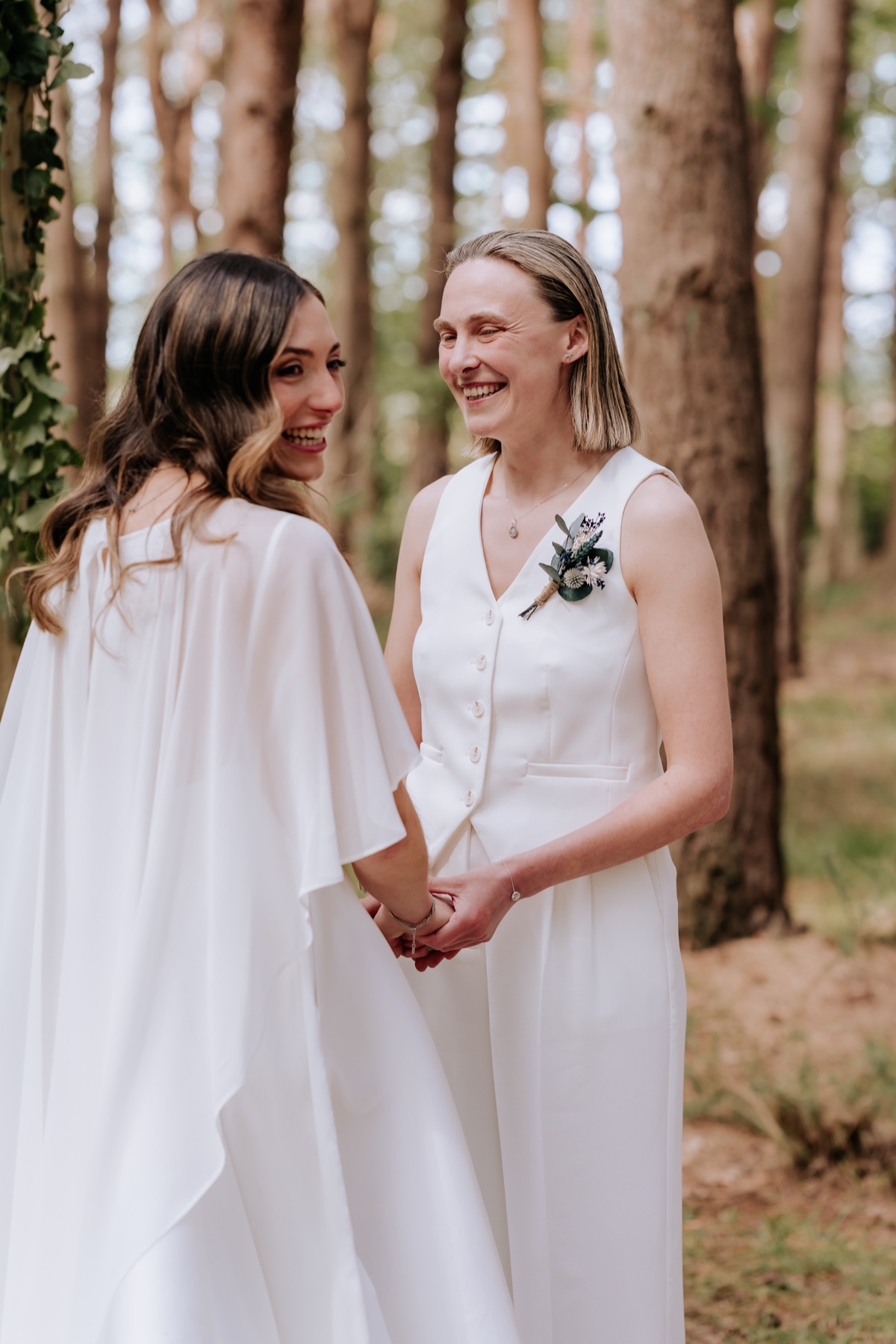 Hannah and Donna holding hands during their woodland wedding ceremony at Harvest Moon.