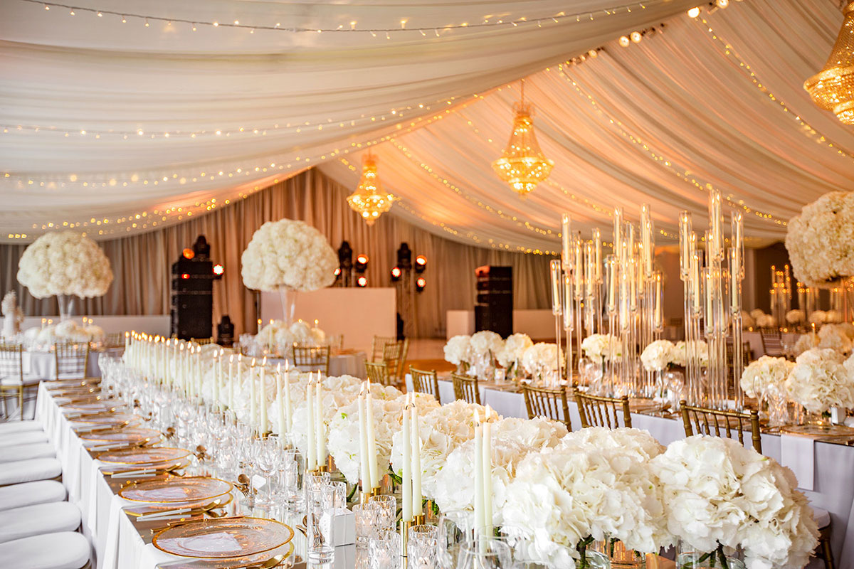 dinner set up with large white floral arrangements, gold candles and cream table clothes at mar hall