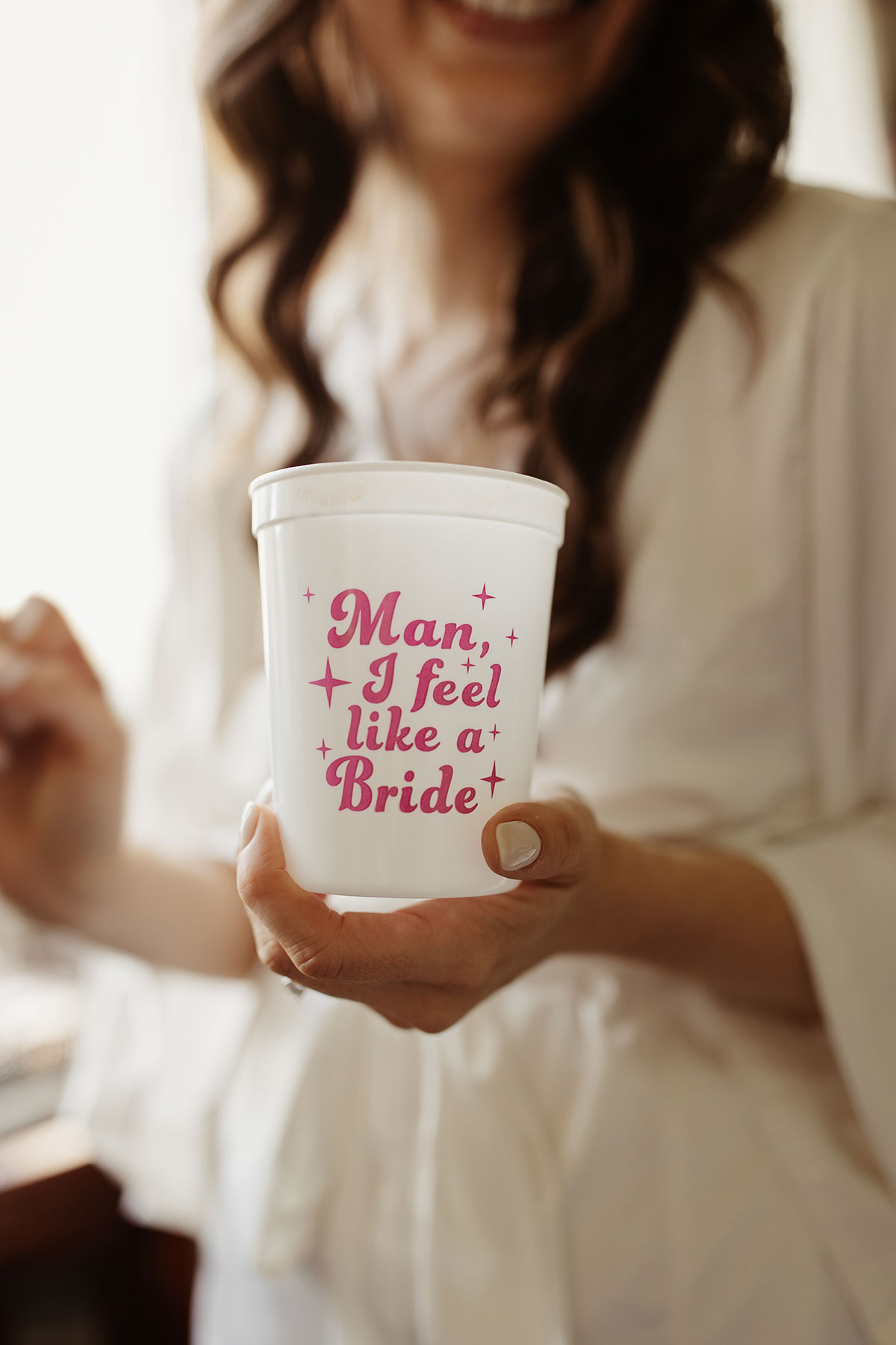 a white disposable plastic cup that reads 'Man I feel like a bride' in pink lettering
