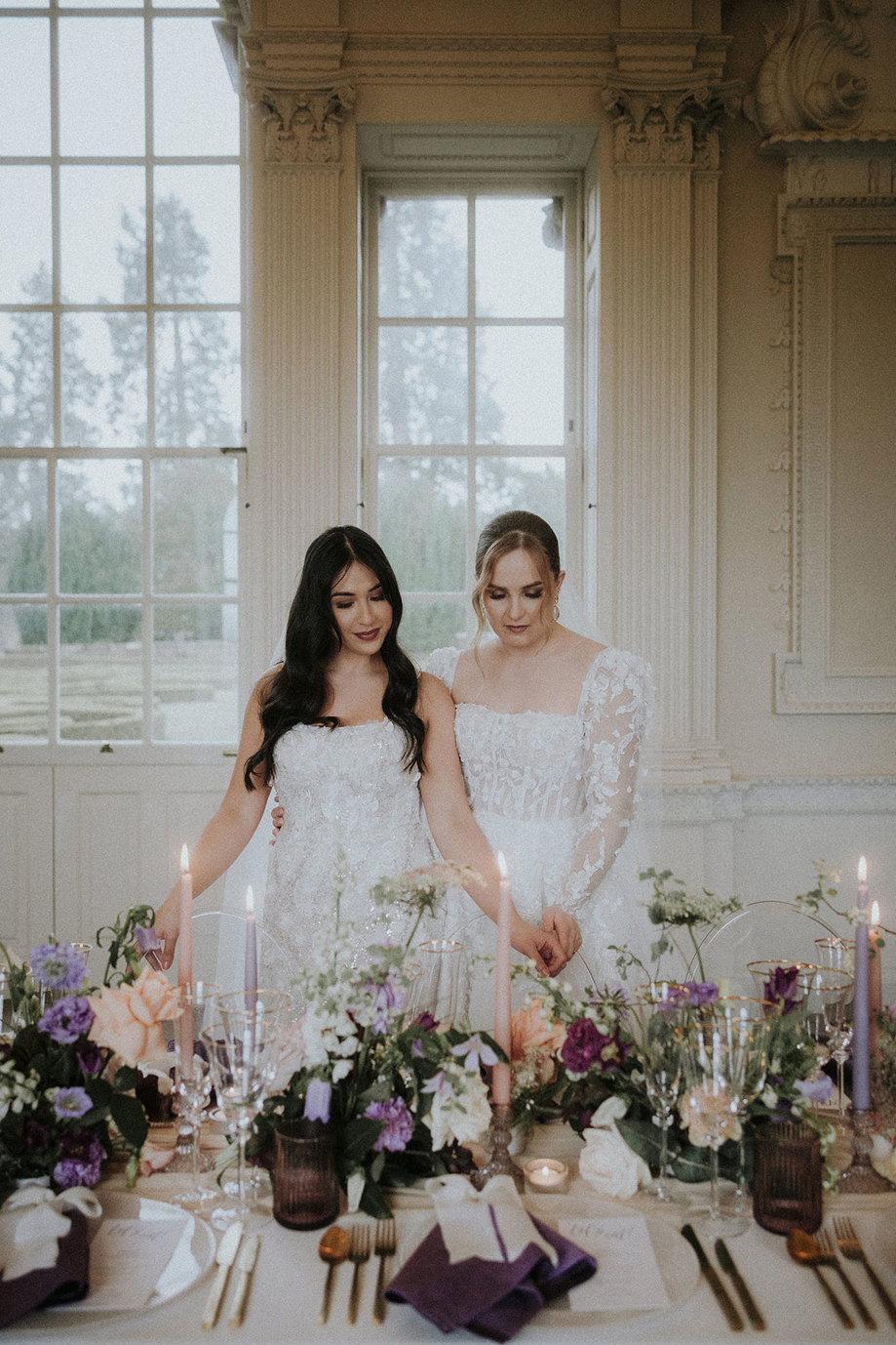 brides lighting candle on dining table with floral arrangement Chatelherault shoot