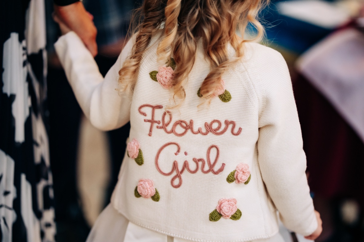 Flower girl's personalised cardigan featuring embroidered pink flowers and 'Flower Girl' lettering at Robyn and James's Glasgow wedding.