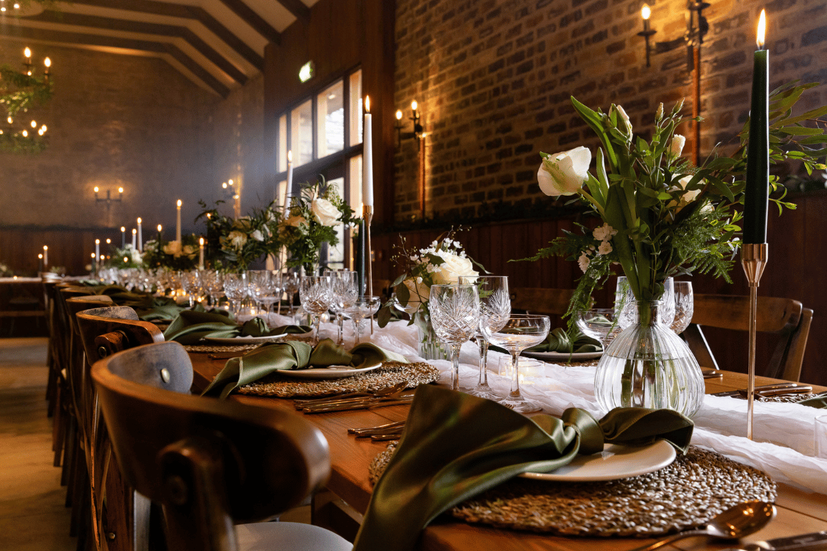 Wedding reception table at Rosebery Steading in Midlothian styled with green napkins, white flowers, candles and glassware
