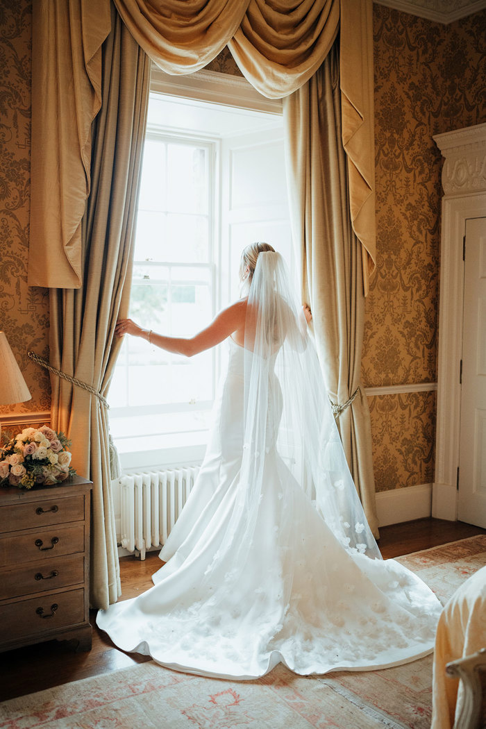 A person in a wedding dress opening a window.