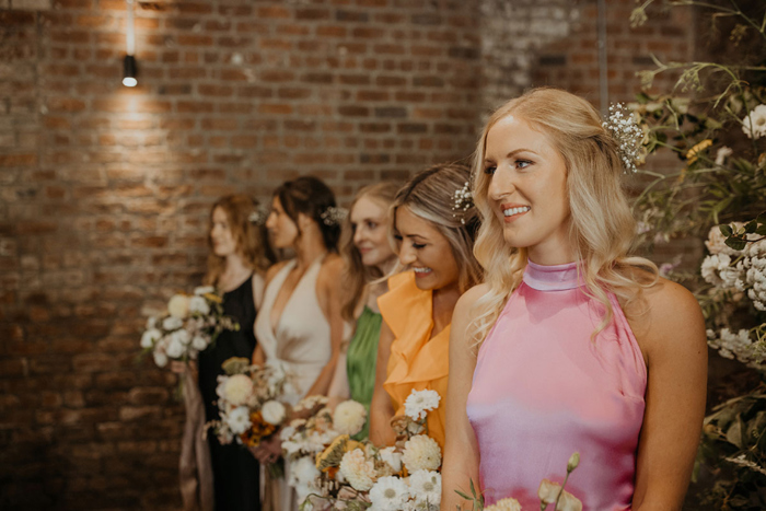 Bridesmaids wearing different colour gowns while waiting at the aisle
