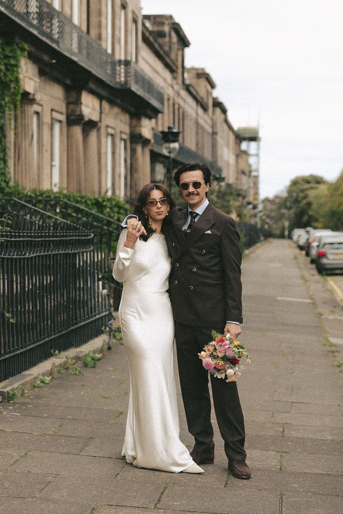 Bride and groom posing together on an Edinburgh New Town street after their wedding ceremony.