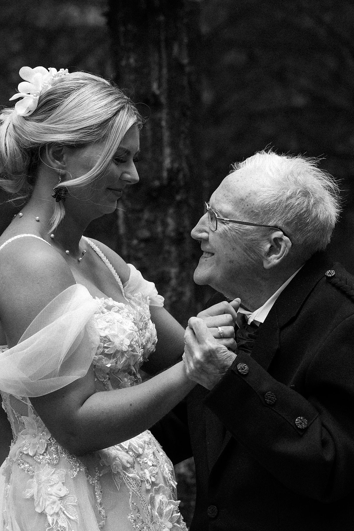 Bride holding hands with an elderly family member during an emotional moment at a Scottish woodland wedding