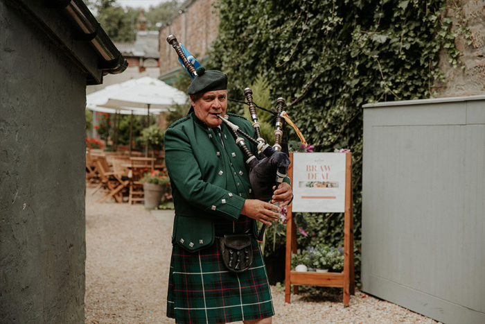 A man in a green kilt playing the bagpipes