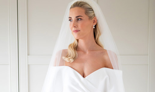 a blonde bride wears a pearl headband and veil, smiling and looking to the side