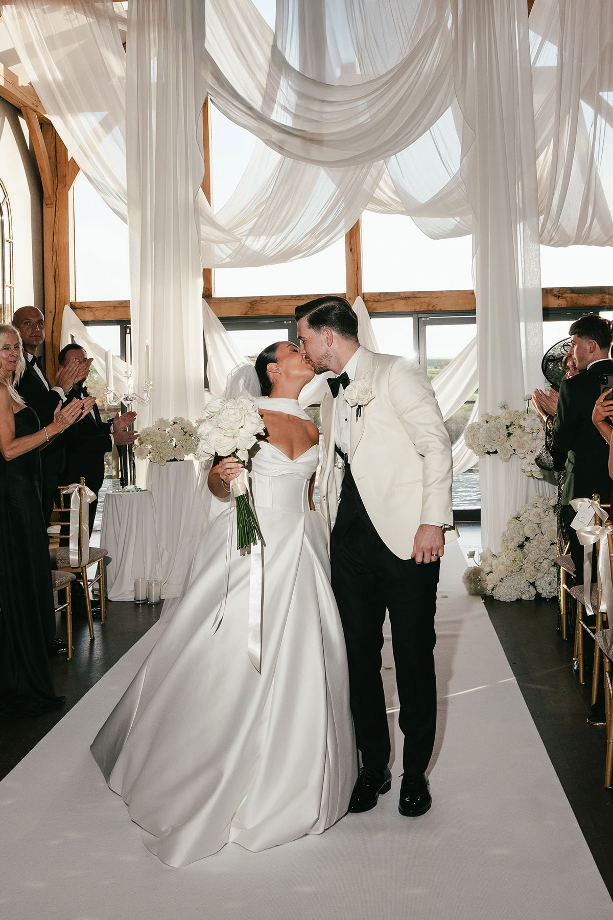Bride and groom kissing during wedding ceremony at Enterkine Country House with draped aisle styling