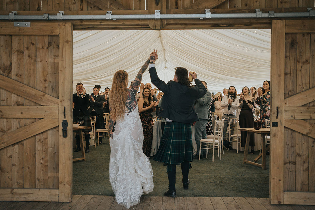 bride and groom cheer as barn doors open up to their guests as eden leisure village is set up for wedding dinner