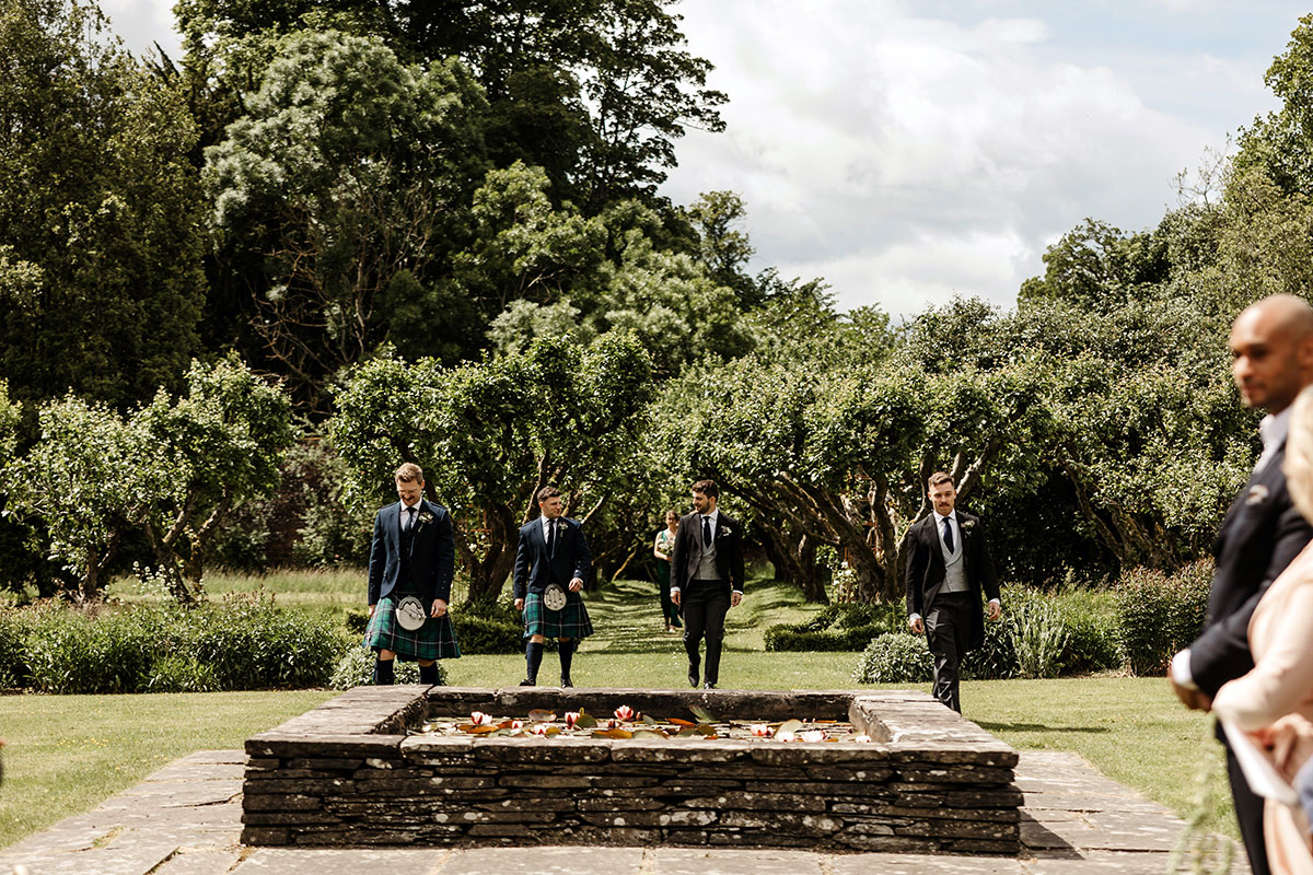 Groomsmen walking on the grass in the grounds of The Byre at Inchyra