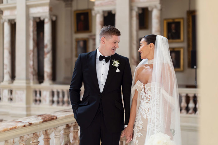 A groom in a Forbes Tailoring tuxedo and bride in an Opus Couture wedding dress. They are standing on a staircase at Gosford House.