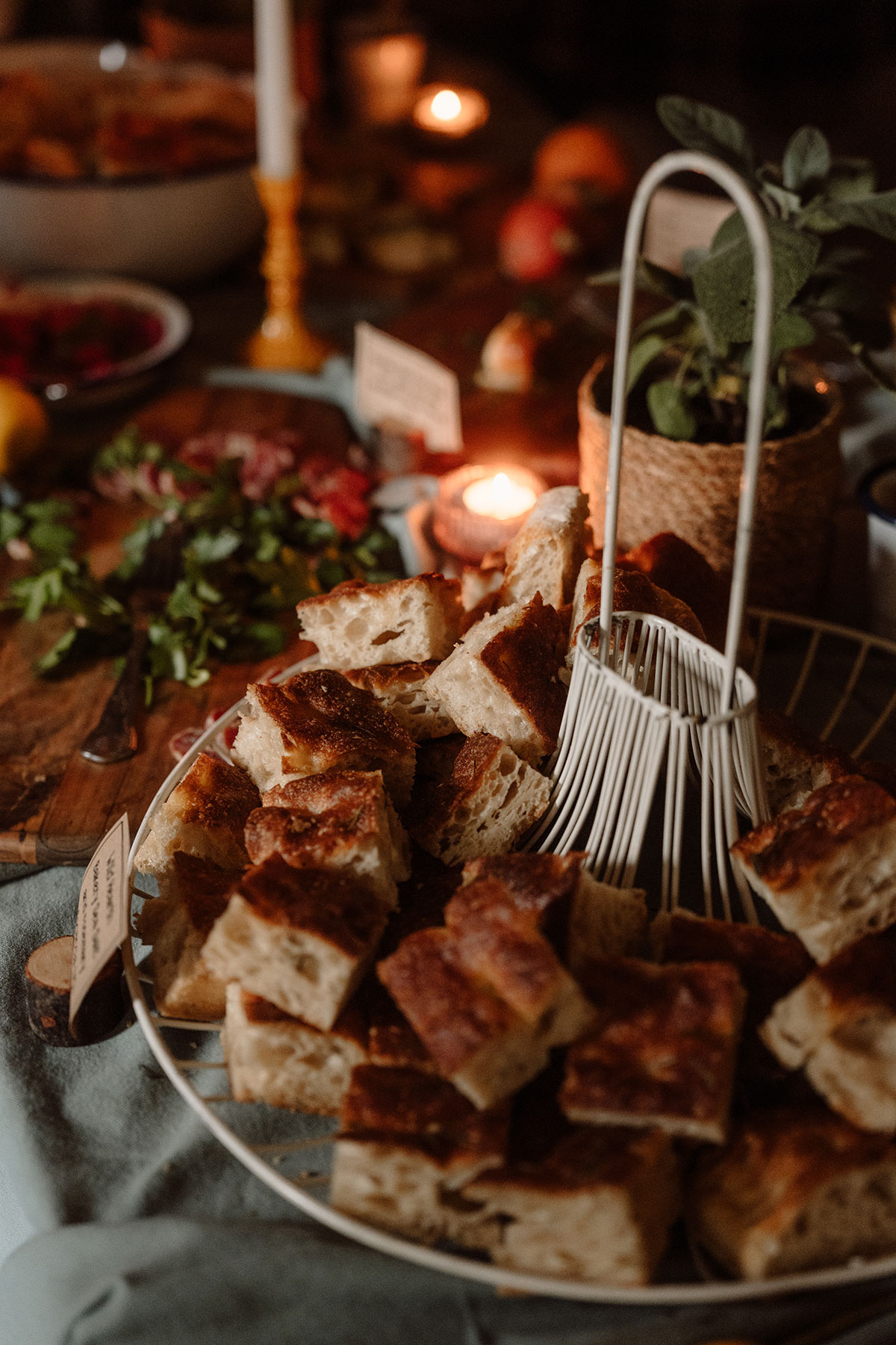 Fresh focaccia bread served on a wedding grazing table, surrounded by candlelight and seasonal décor