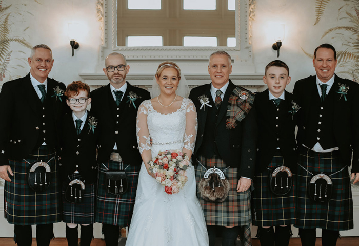 Bride in the middle of the six groomsmen all wearing Highland attire