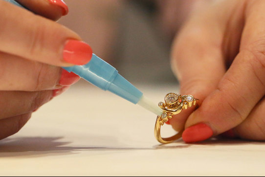 a pair of manicured hands cleaning a gold diamond ring