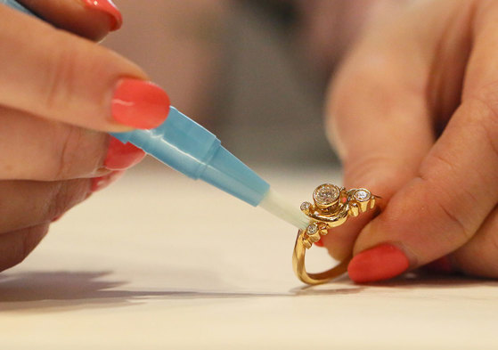 a pair of manicured hands cleaning a gold diamond ring