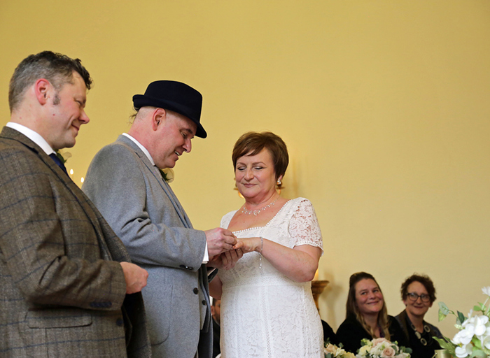 A groom placing the ring on his bride's finger during their wedding ceremony