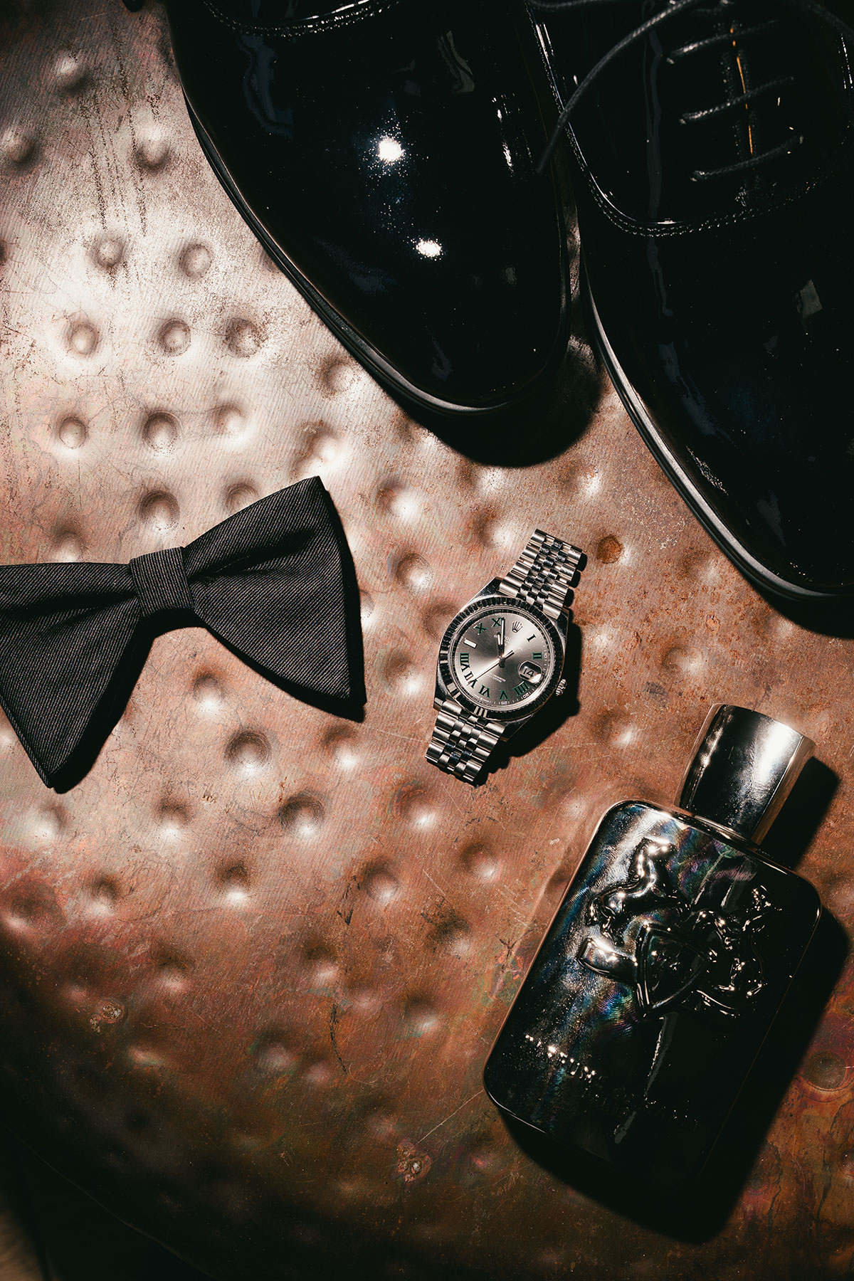 Groom detail flatlay with bow tie, watch, shoes and cologne for wedding morning styling