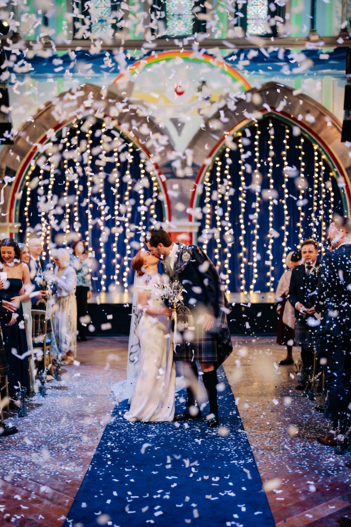 Newlyweds Robyn and James share a kiss beneath a shower of white confetti during their Òran Mór wedding in Glasgow.