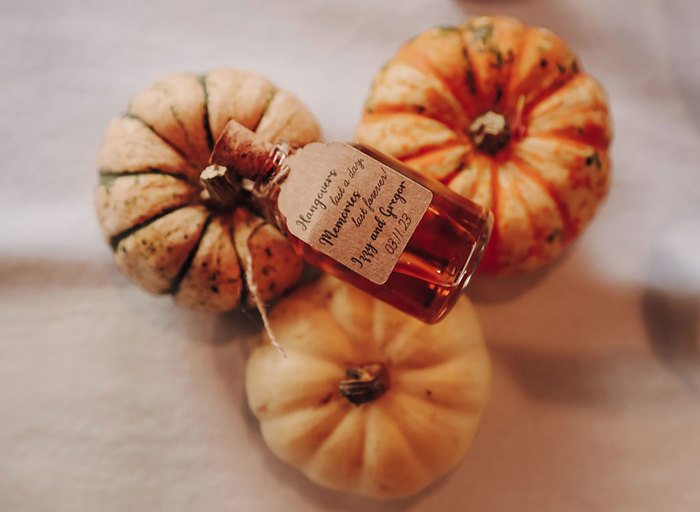 three small pumpkins with a miniature alcohol wedding favour in glass bottle