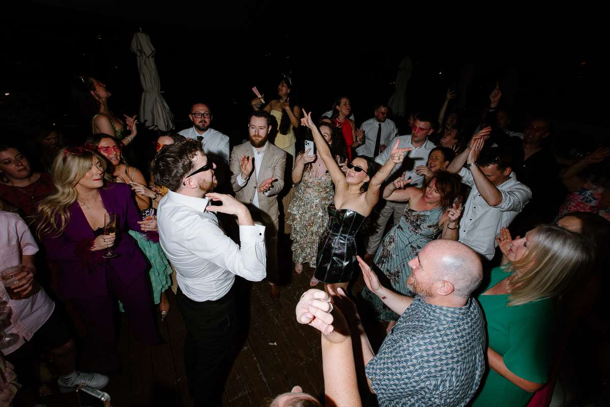 Bride and groom dance among their guests during the evening rooftop wedding party at The Hoxton Barcelona.