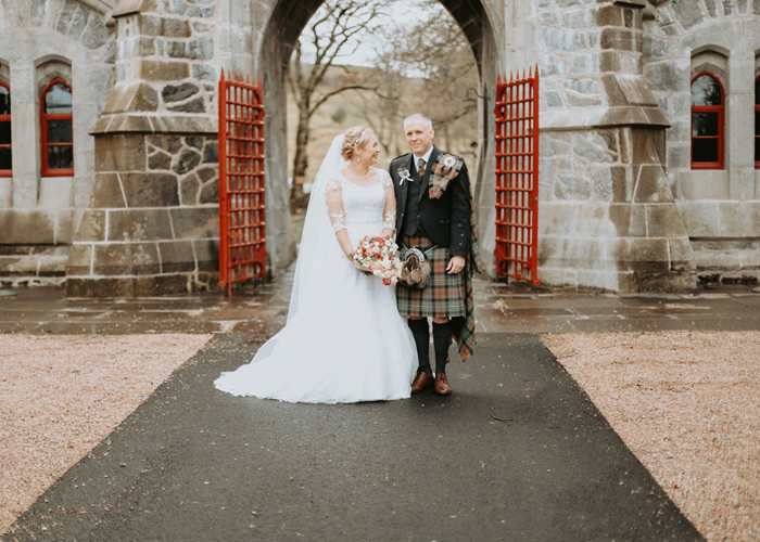 Couple portrait of bride and groom in front of old building with red gate