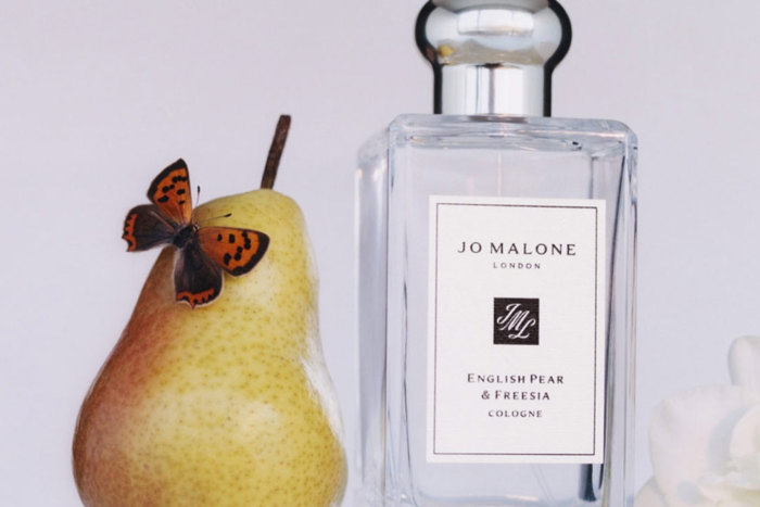 pear with a butterfly on it next to a bottle of Jo Malone cologne