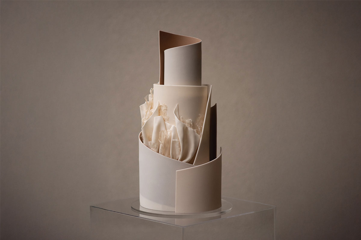 a wedding cake in cream and beige tones with an angular and ruffle-effect structured fondant design