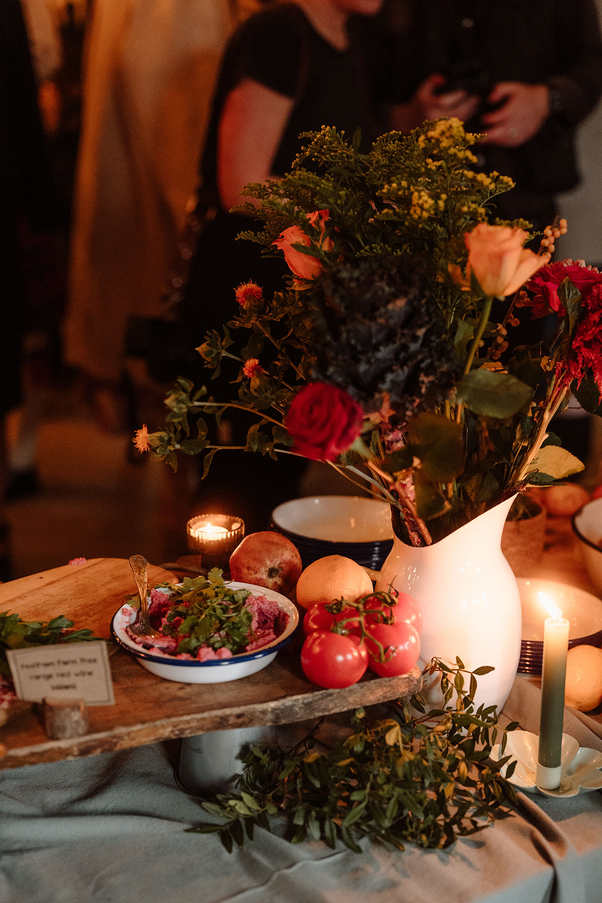 Colourful wedding table styling featuring fresh flowers, candles, fruit and sharing platters at an industrial wedding venue