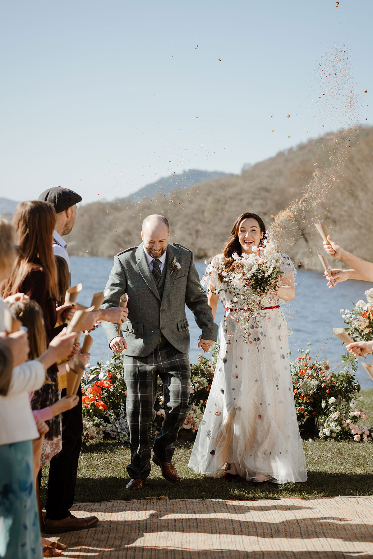 Bride and groom newly married, walking down the aisle as guests throw confetti 