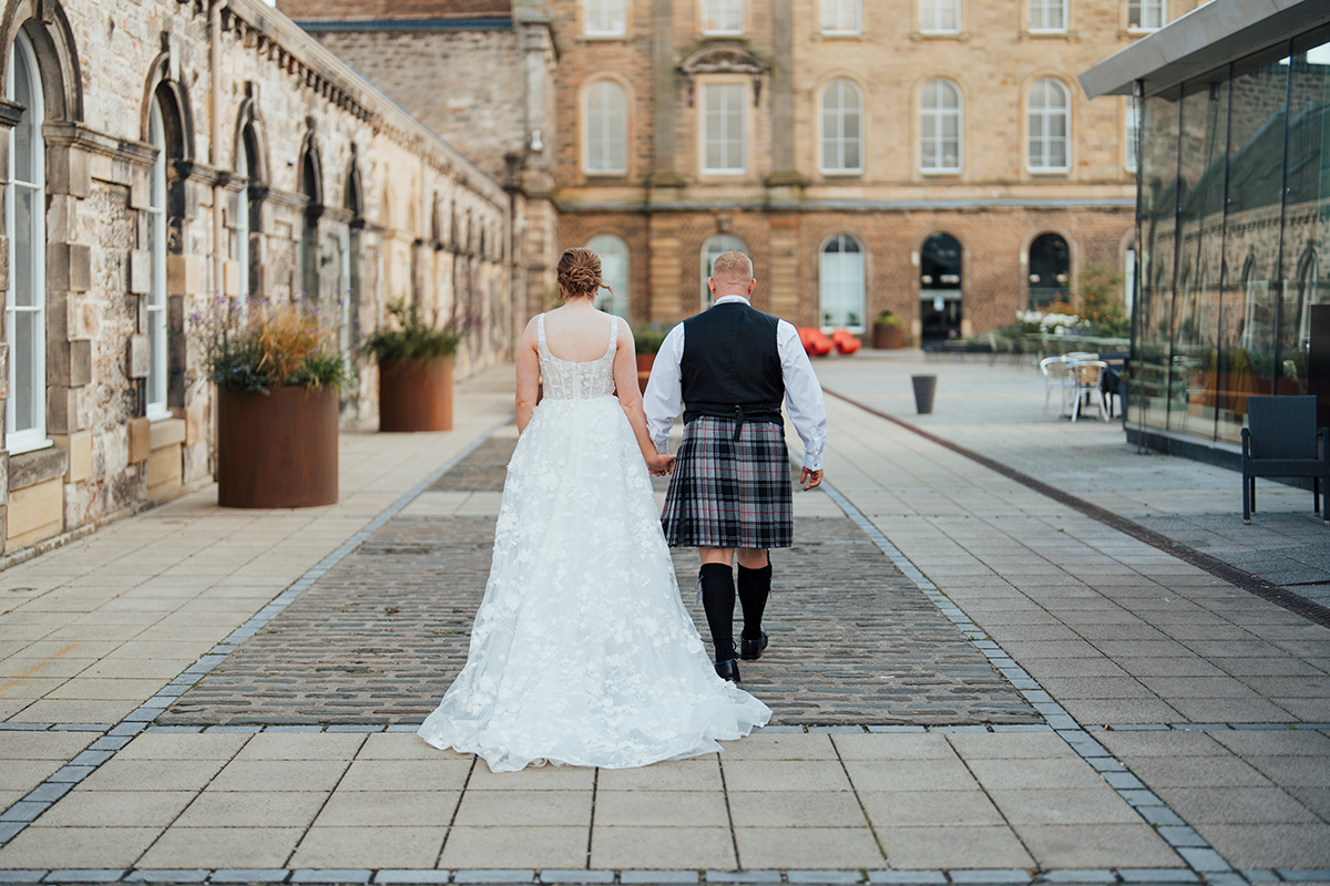 Bride and groom walking through courtyard at The Venue Eskmills wedding venue in East Lothian