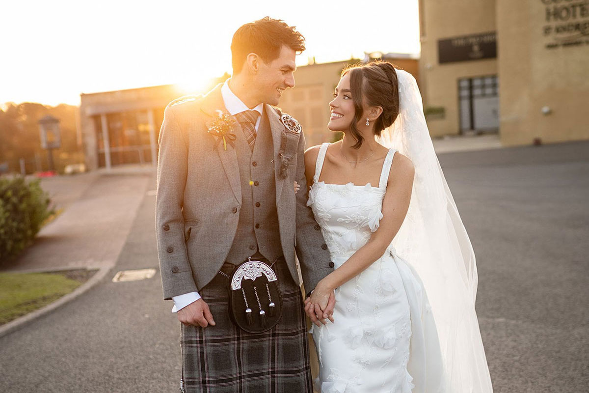 Bride and groom walking at sunset outside Old Course Hotel in St Andrews during elegant Scottish wedding.