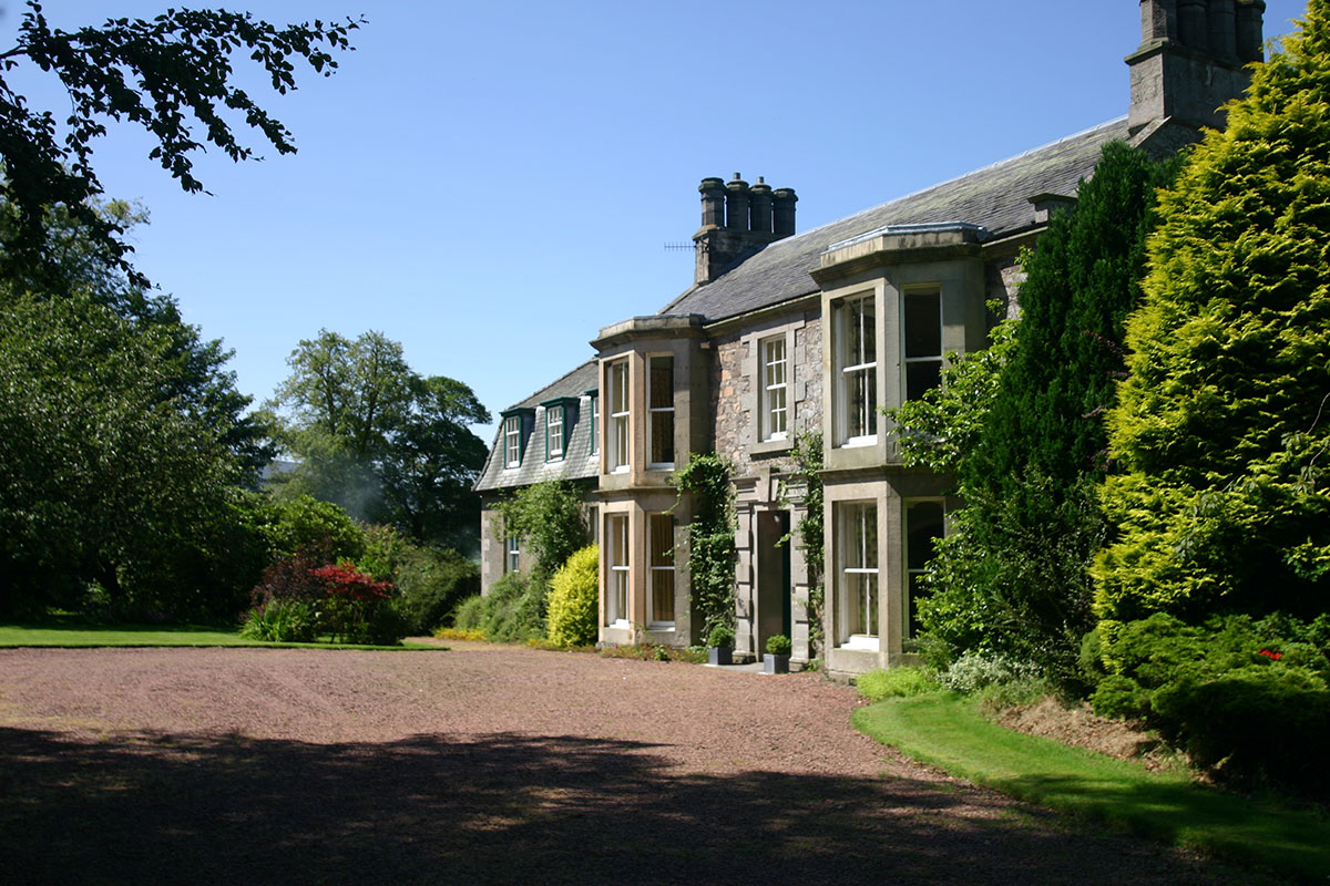 Exterior view of Cormiston Farmhouse with stone walls, sash windows and surrounding gardens