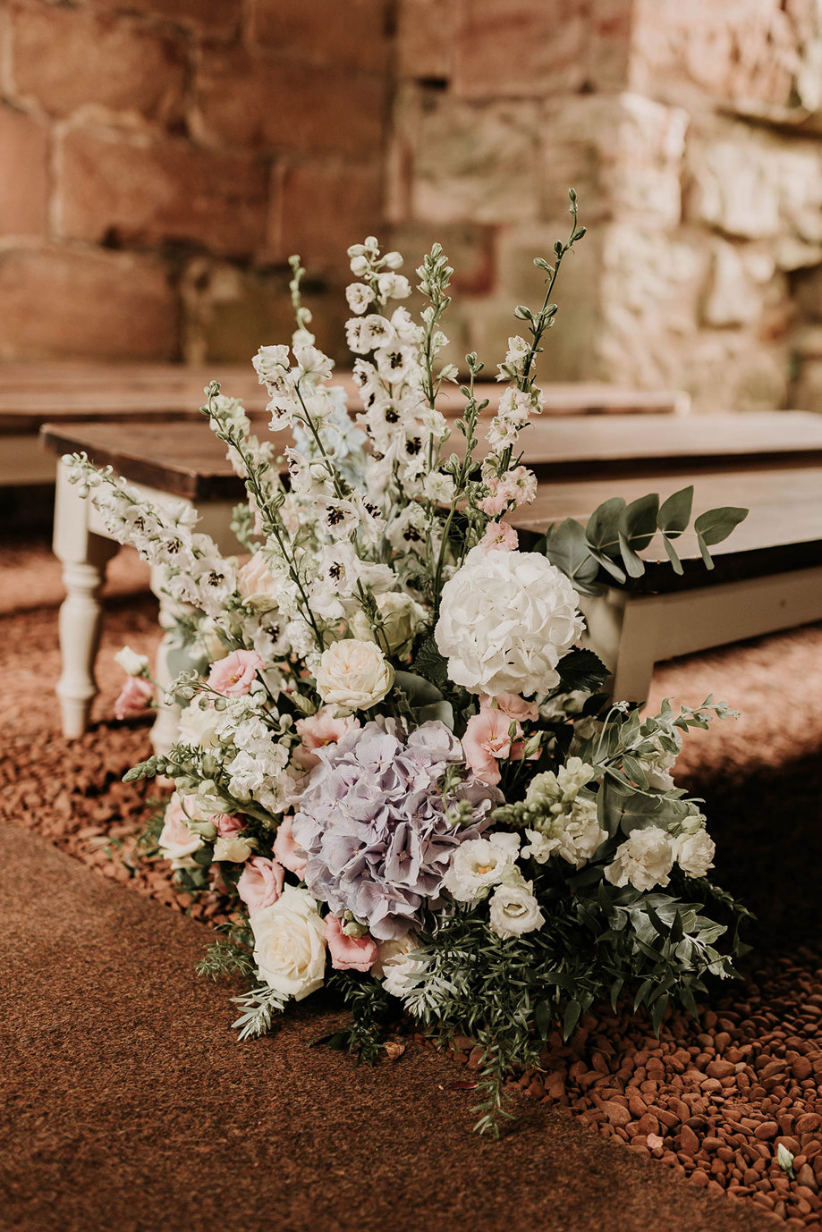 a cluster of pastel flowers on the floor at the end of a pew in Dunglass Collegiate Church
