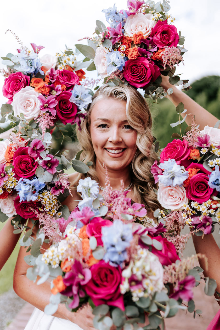 a bride posing with colourful bouquets forming a frame around her face