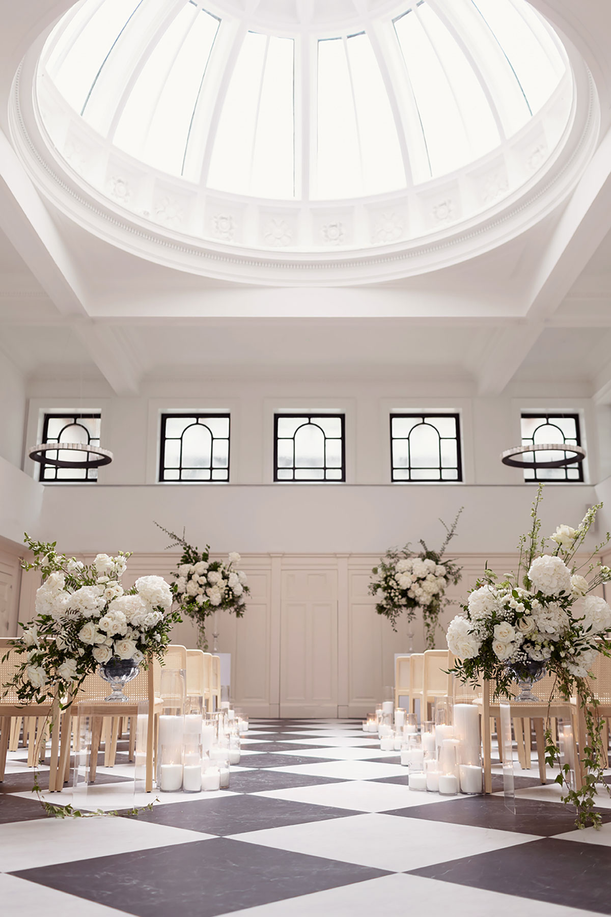 Wedding ceremony setup at The Collector’s Hall Glasgow with black-and-white floor, domed ceiling, candles, and white flowers