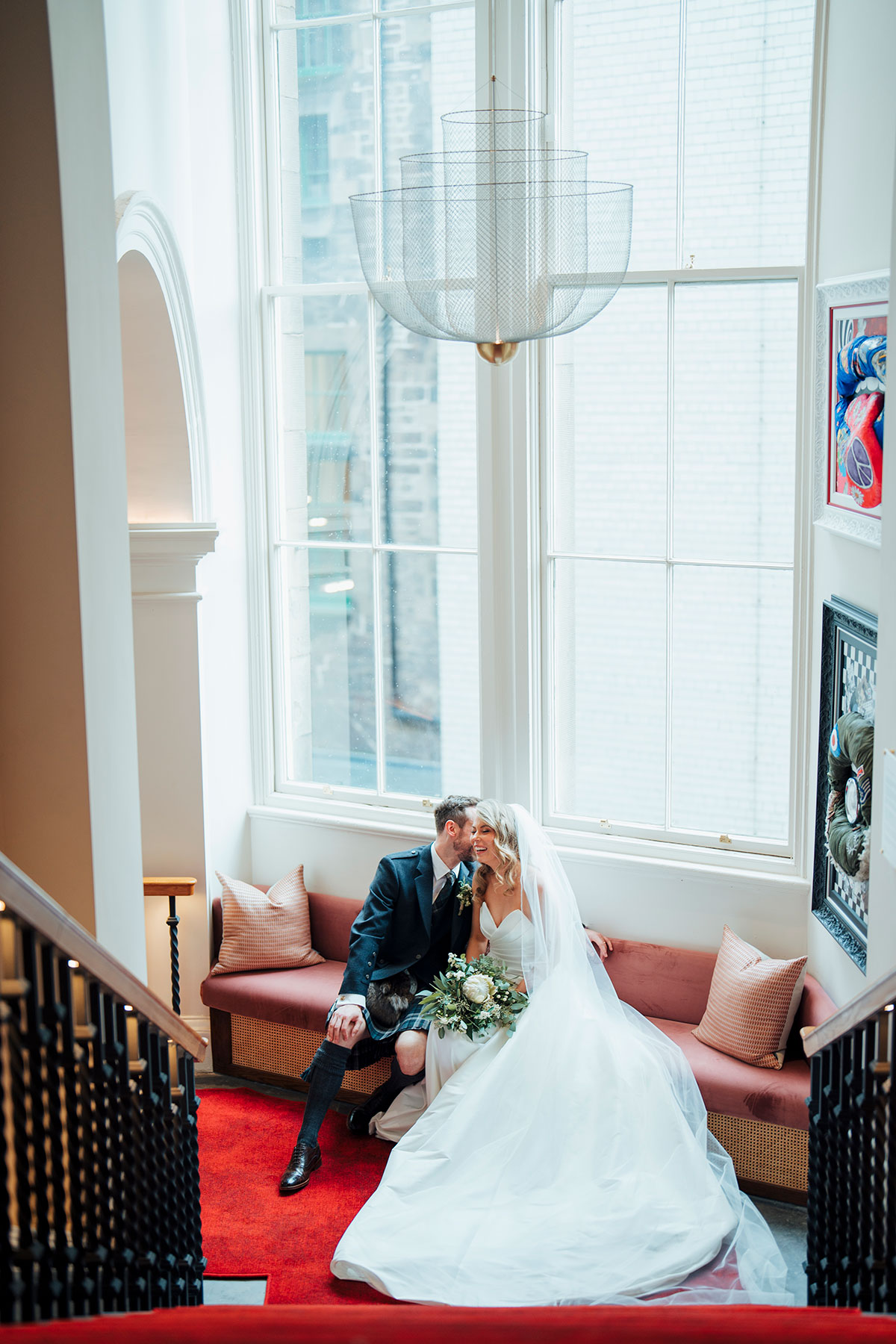 bride and groom laugh next to large wedding during wedding at Virgin Hotels Edinburgh