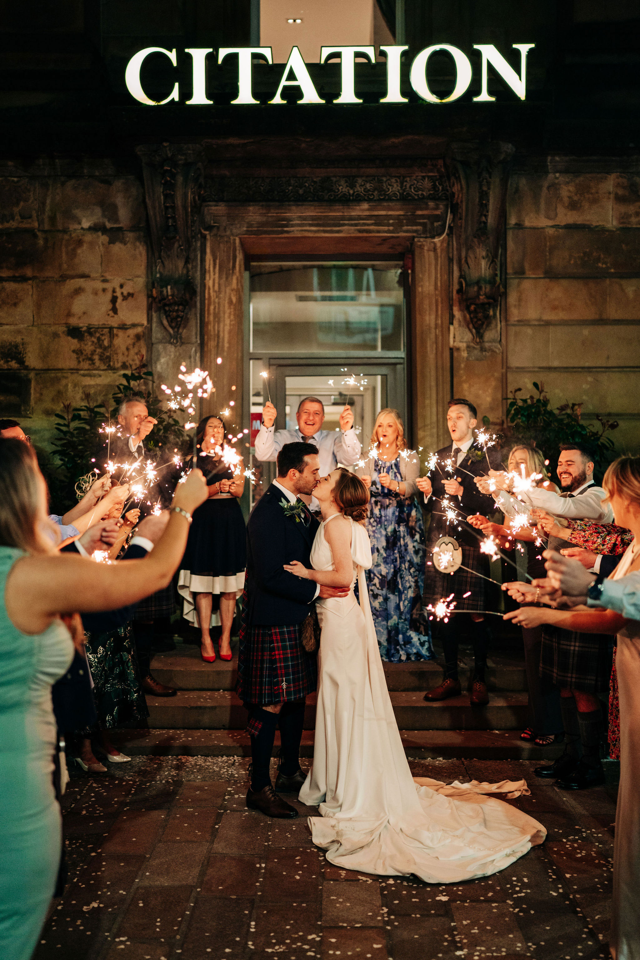 bride and groom kiss outside citation glasgow as guests hold sparklers