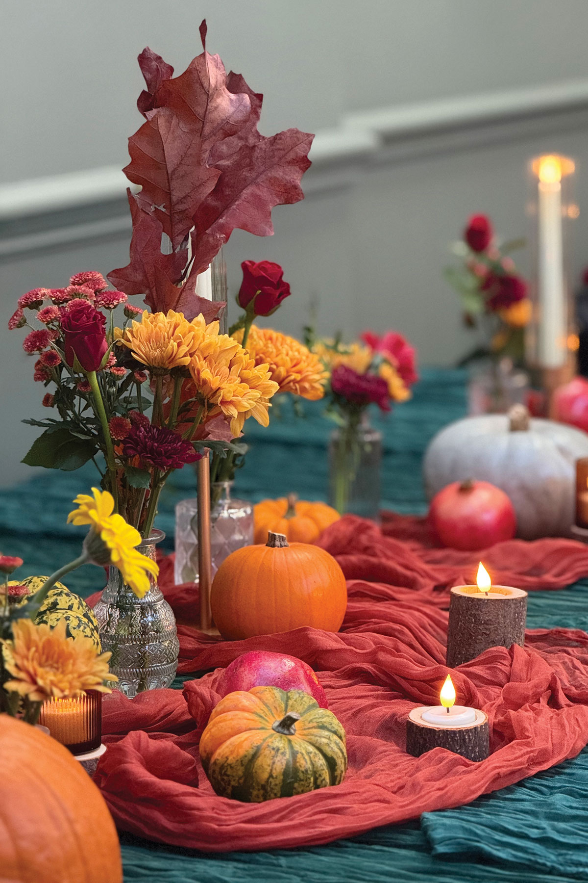 Autumn-inspired wedding tablescape with pumpkins, candles, colourful flowers and draped fabric runner