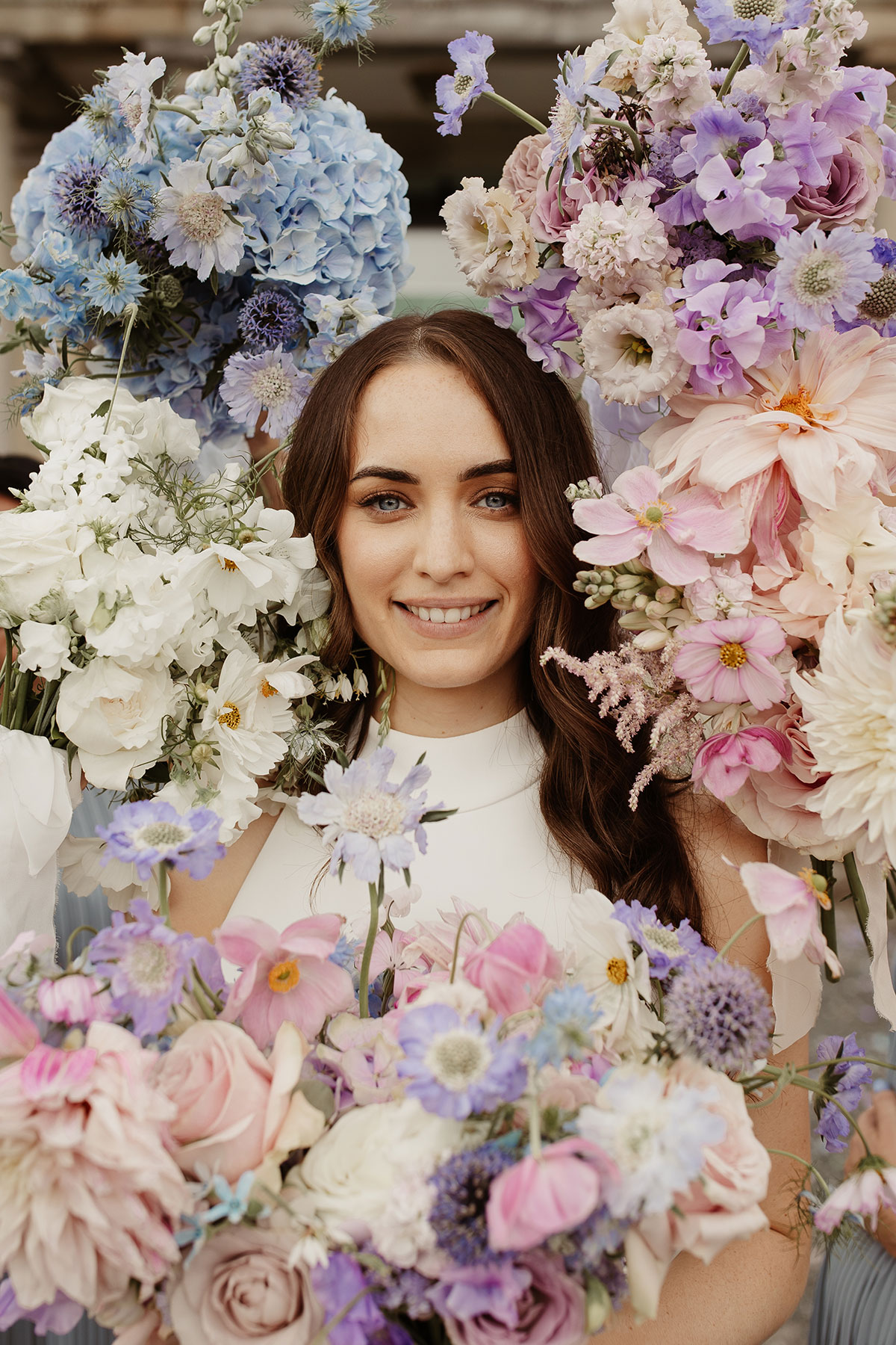 a bride's face framed by pastel-coloured flower bouquets